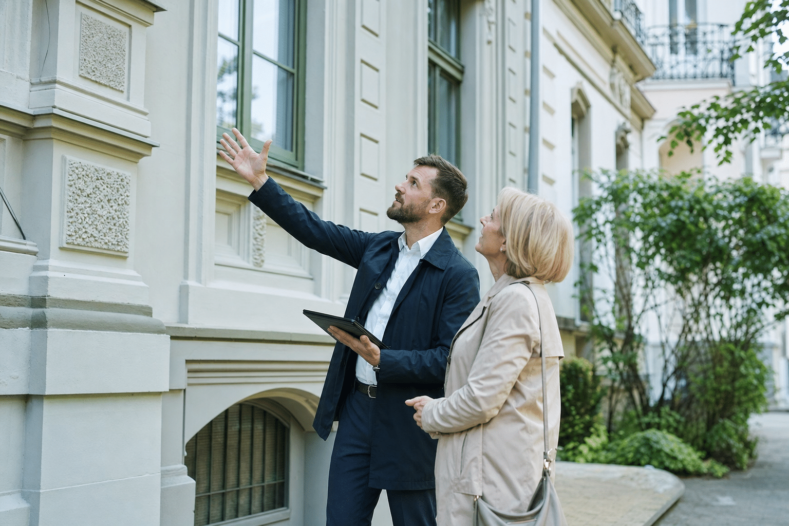 Sachverständiger besichtigt mit einem Eigentümer die Fassade eines Wohnhauses